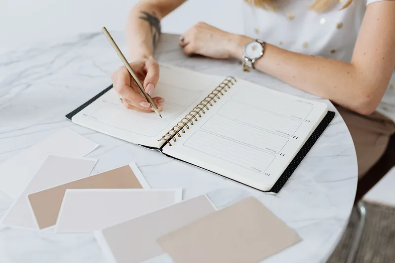 Woman writing notes in a planner on a table
