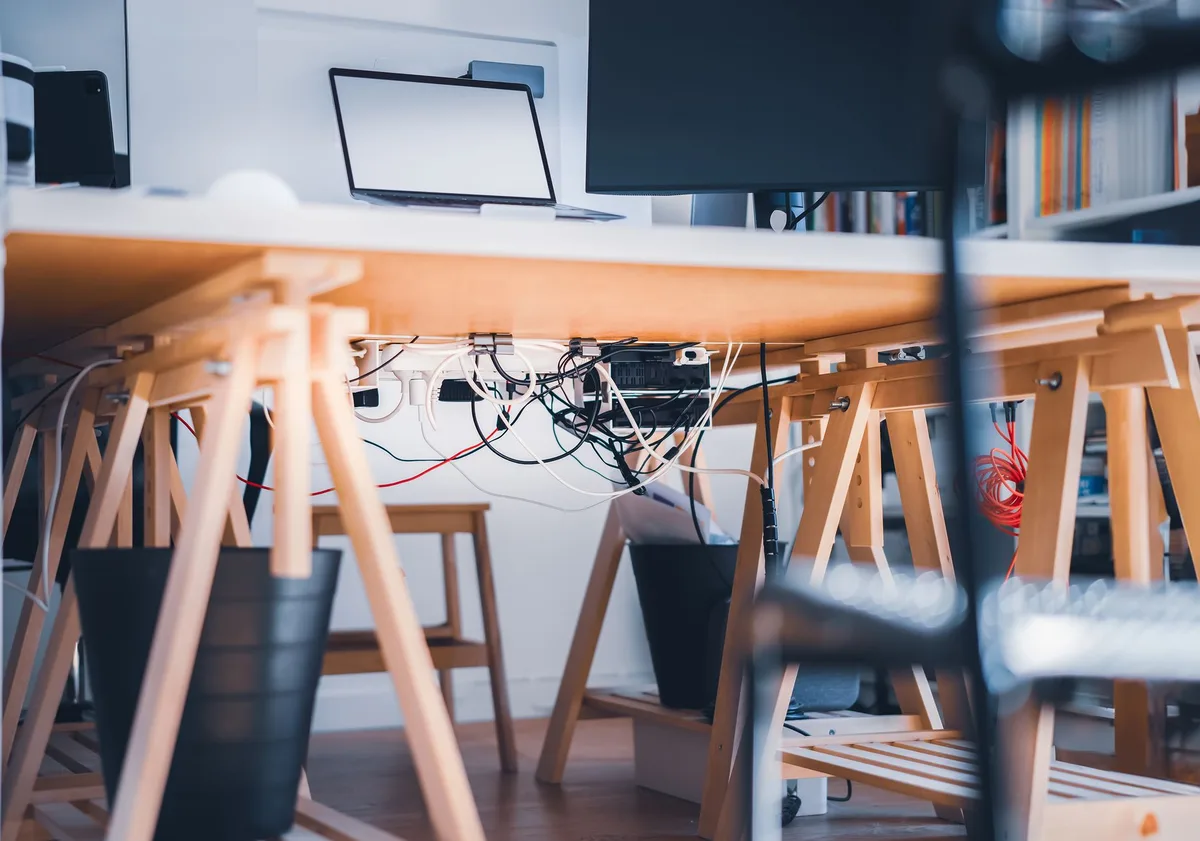 A stylish workspace with visible cables connecting a laptop and monitor, representing an evergreen funnel system wired together