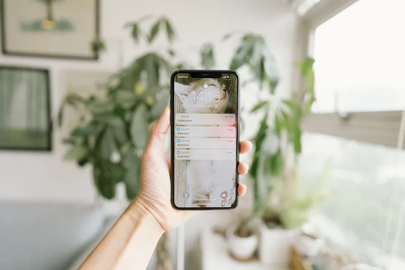 A hand holding a smartphone displaying a notification, representing an alert for a broken funnel system