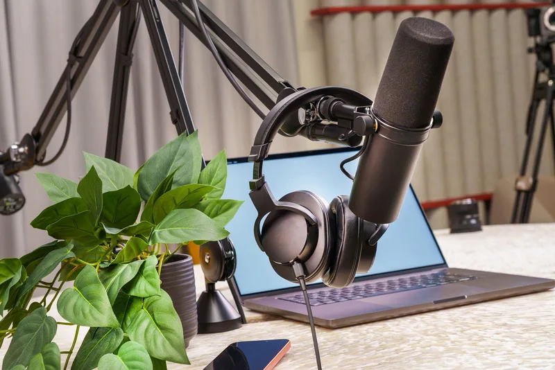 Recording setup with a microphone, headphones, and laptop on a desk, for capturing an evergreen webinar