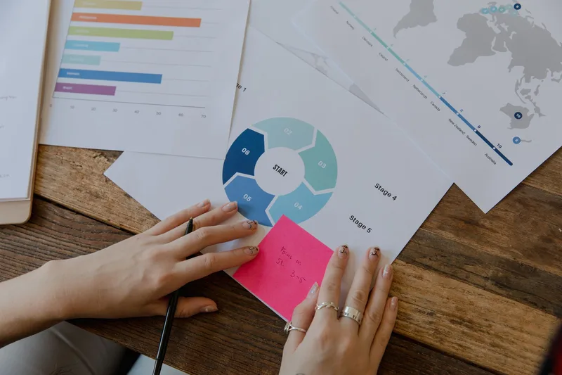 Close-up of hands reviewing printed charts and notes on a desk