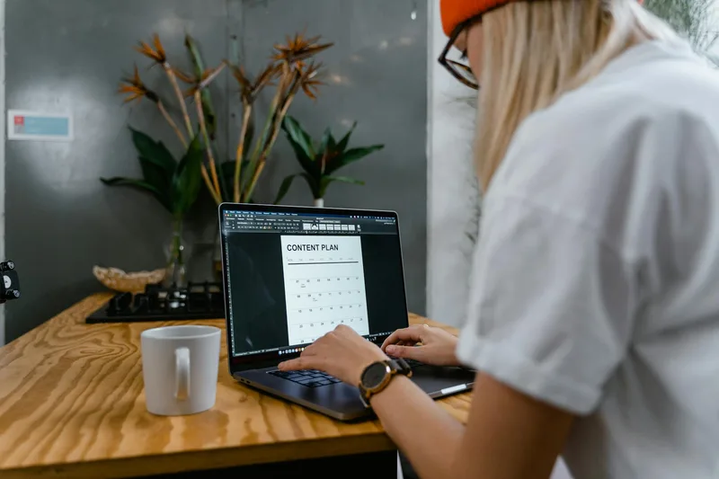 A laptop showing a long-form webpage with visible text sections and a clear call-to-action button above the fold, on a clean white desk with natural window light
