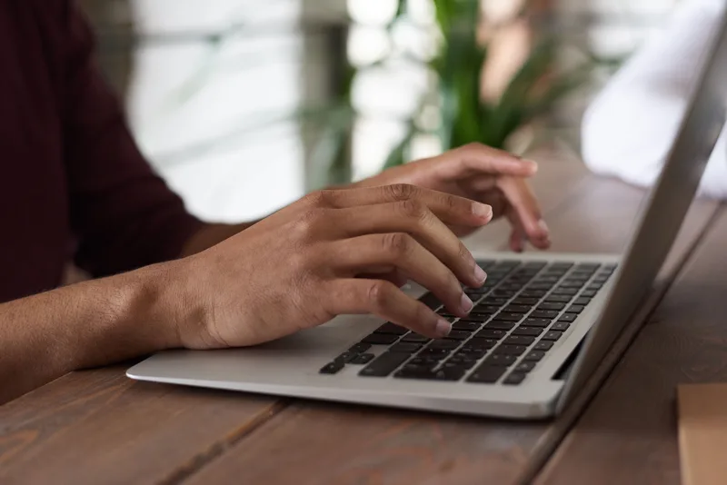 Close-up of hands typing on a laptop keyboard