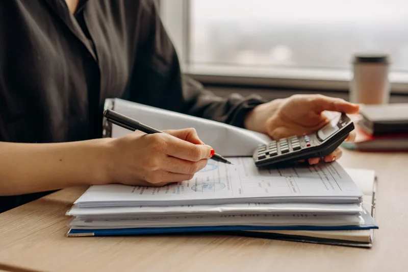 Person using a calculator with financial documents on a desk