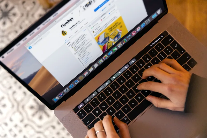 Hands typing on a laptop keyboard while a browser page is open on the screen