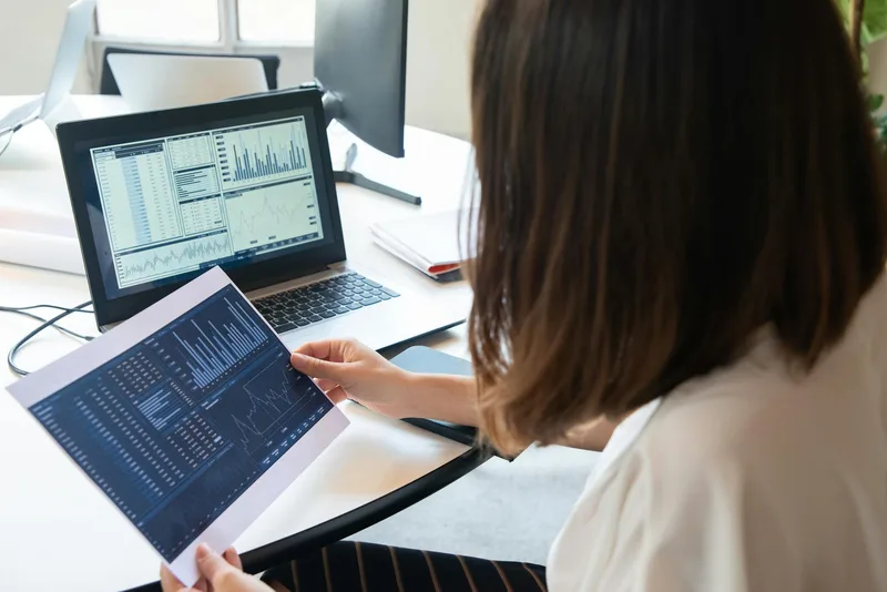 A creator at a desk comparing two weeks of analytics side by side, looking at conversion rate data on a laptop screen