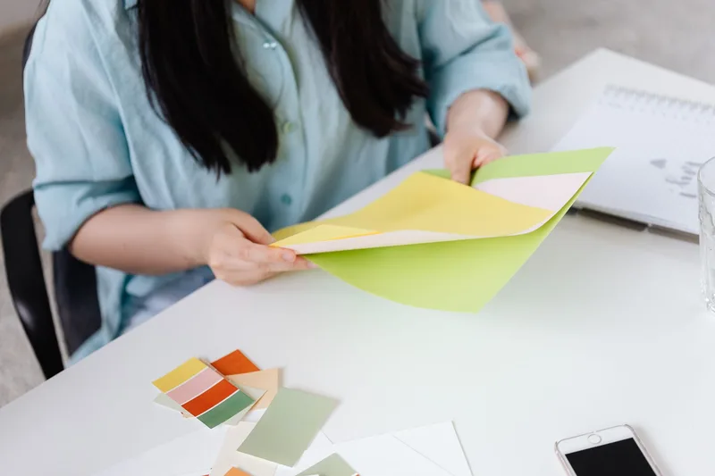 Person examining color samples and comparing options at a desk, representing the decision between competing checkout tools