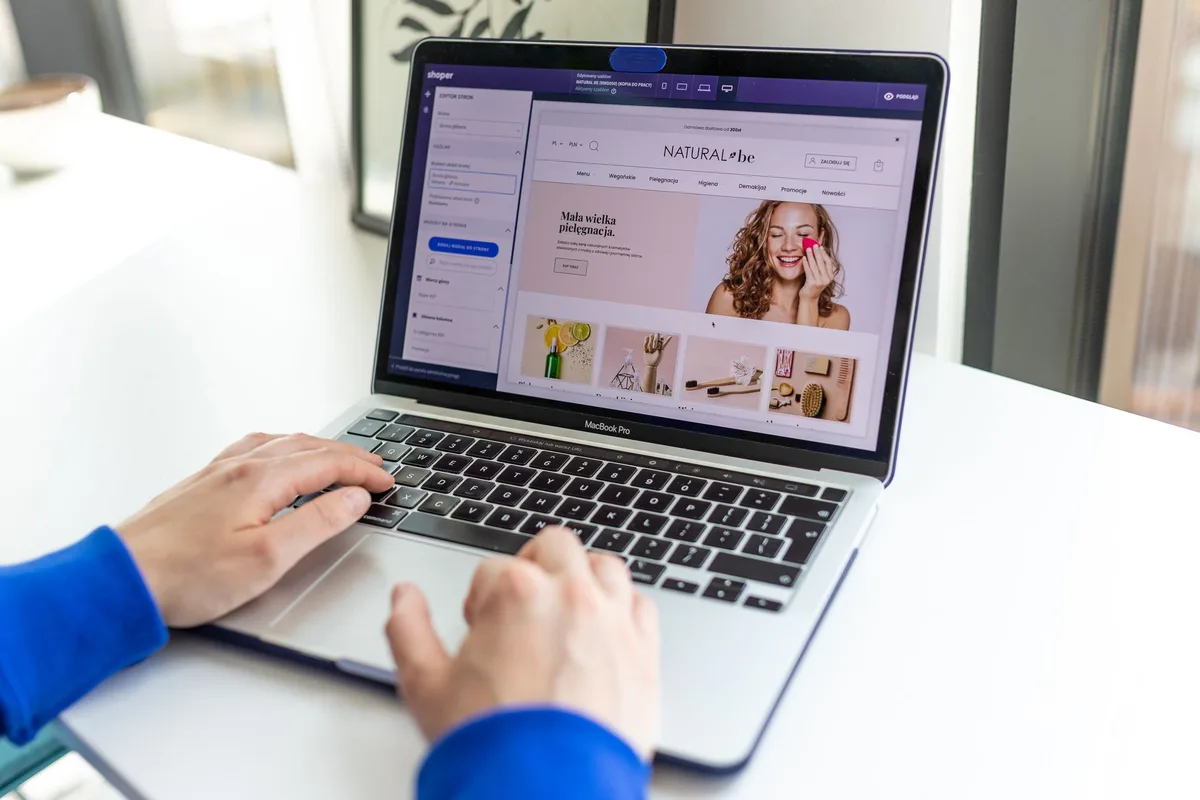Hands typing on a laptop with an online storefront open, researching checkout platforms