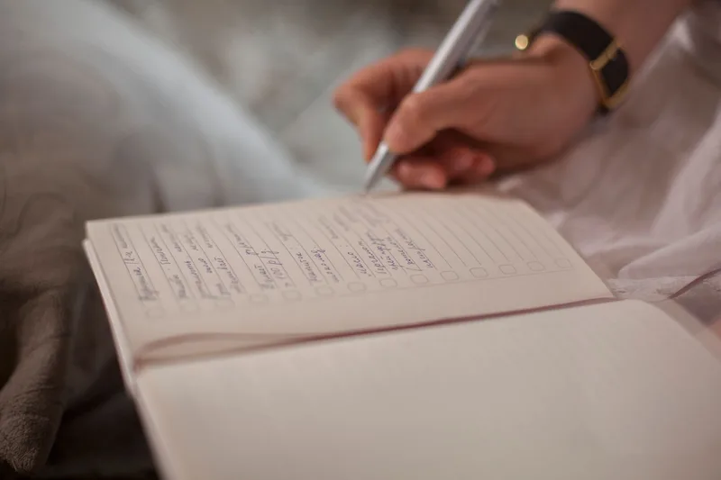 A person writing in a notebook, representing a monthly funnel check-up routine