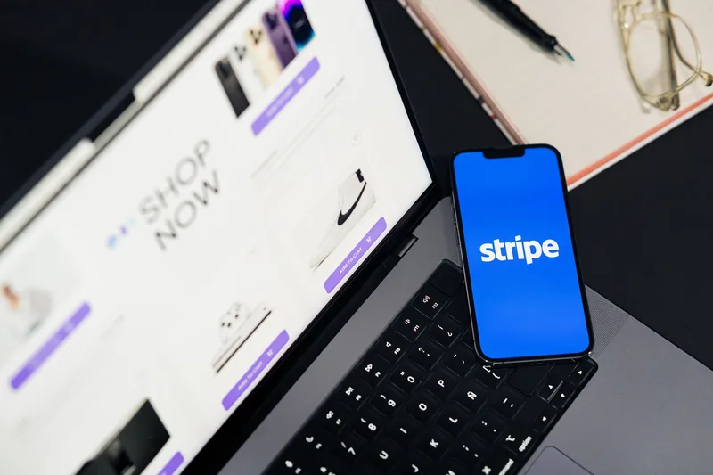 Mobile phone displaying a checkout payment screen next to a laptop
