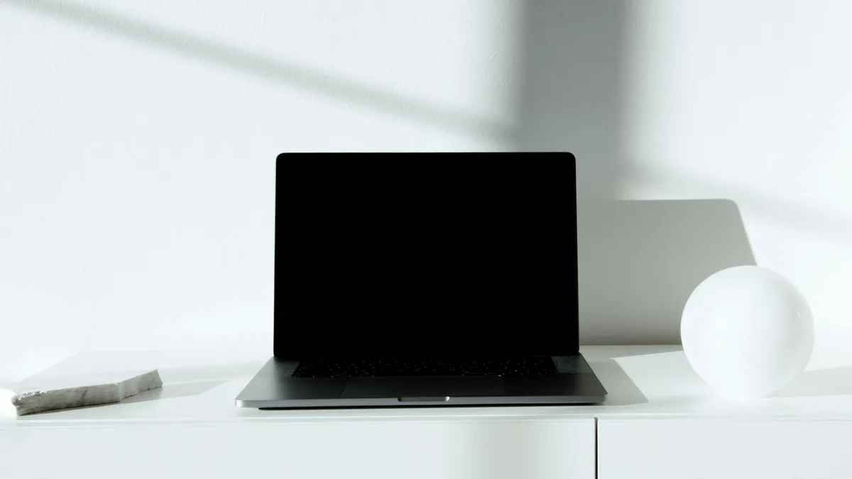 Creator at a minimal desk with laptop open, reviewing a platform decision