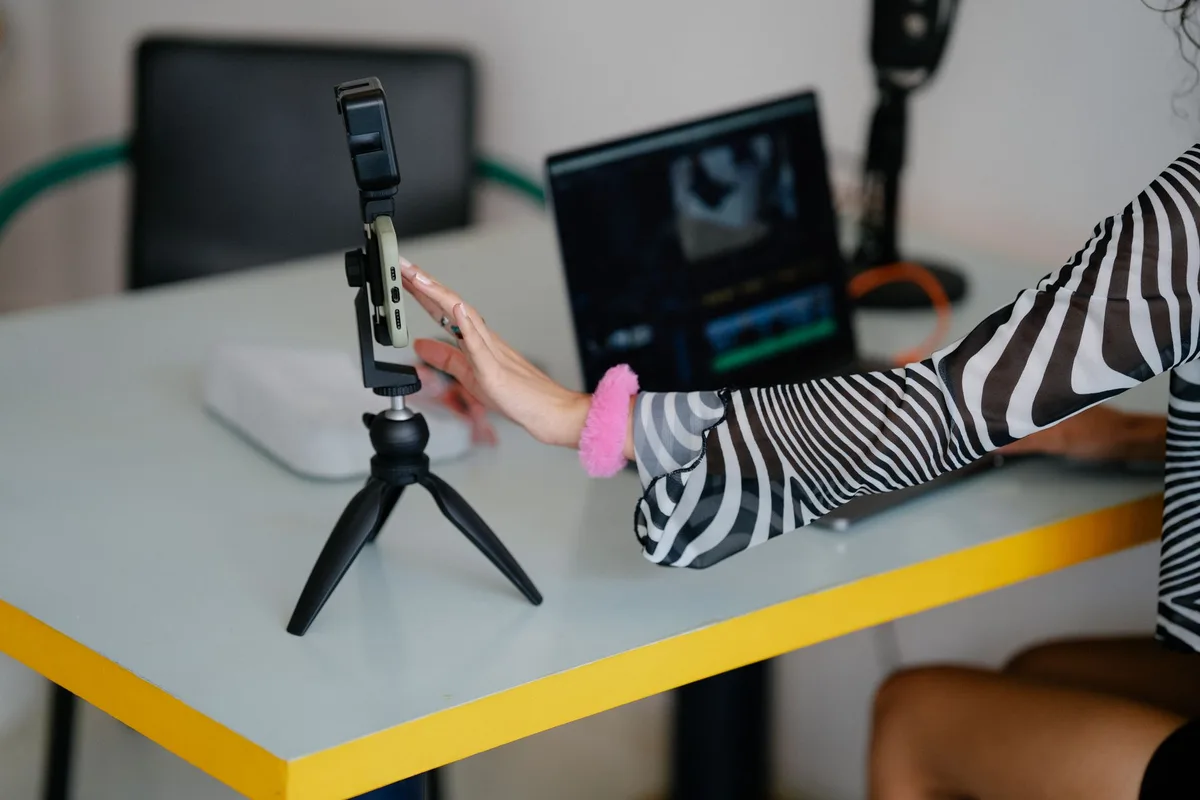 Creator using smartphone and laptop setup for managing an online business from home