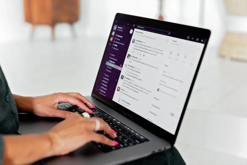 Person typing on a laptop displaying a messaging and communication tool interface