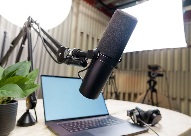 Course creator at a recording setup with a laptop, ring light, and microphone at a home studio desk