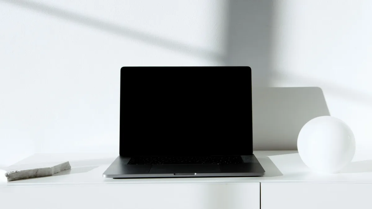 A course creator reviewing two platform options on a laptop at a clean minimal desk
