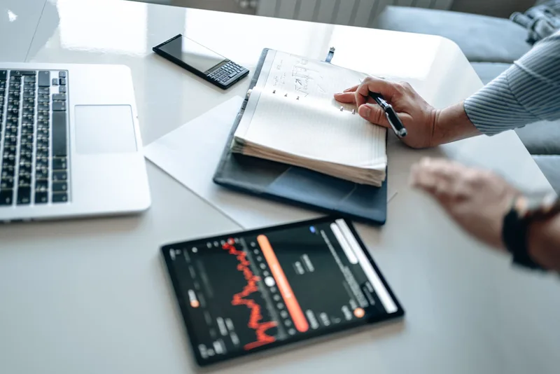 Creator reviewing course platform options on a tablet with a strategic decision flow on a notebook beside it
